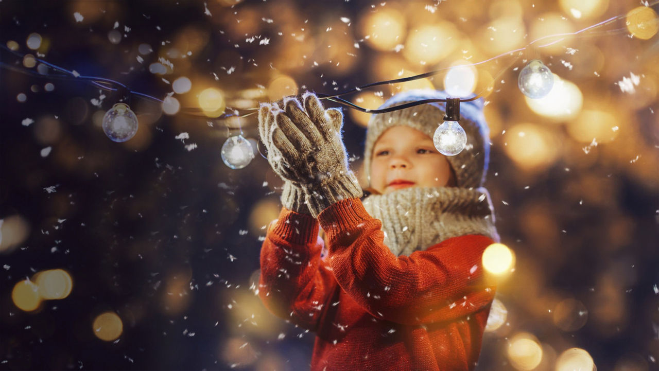 Ein kleines Mädchen fängt mit Ihren Handschuhen Schneeflocken auf