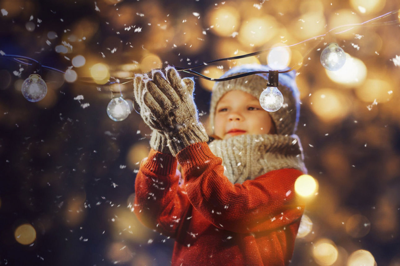 Ein kleines Mädchen fängt mit Ihren Handschuhen Schneeflocken auf