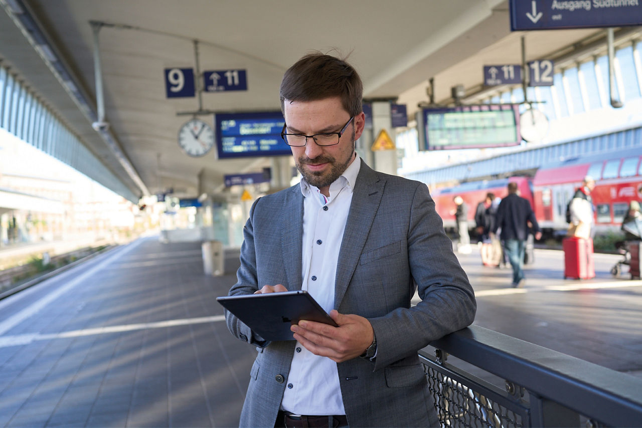 Mann mit Tablet am Bahnhof