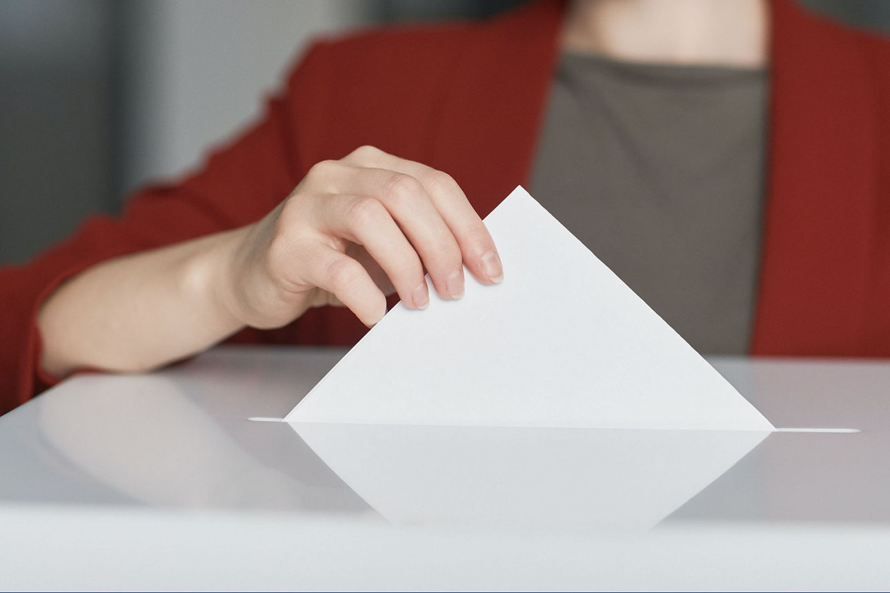 Briefumschlag wird in eine Wahlurne geworfen