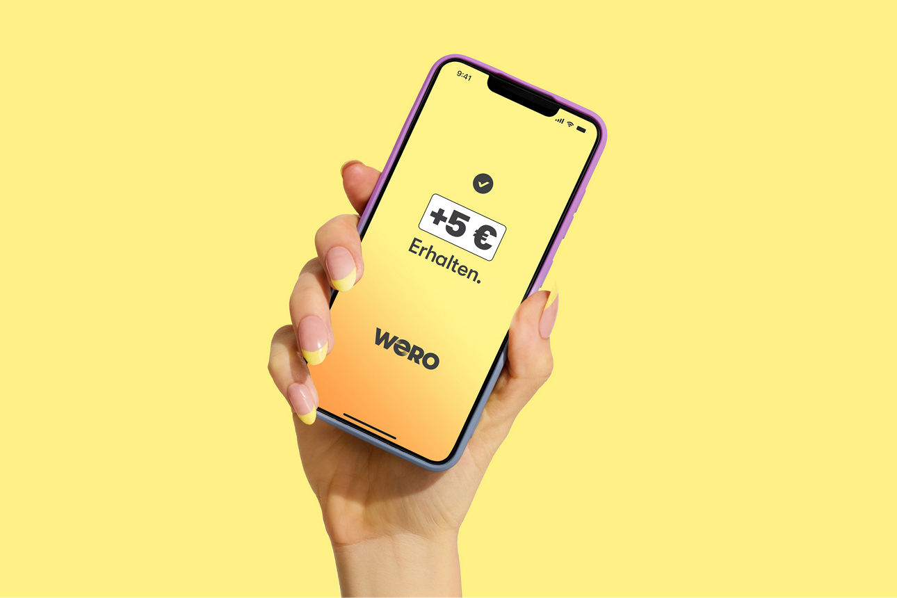 Eine Hand hält ein Smartohone vor einem gelben Hintergrund