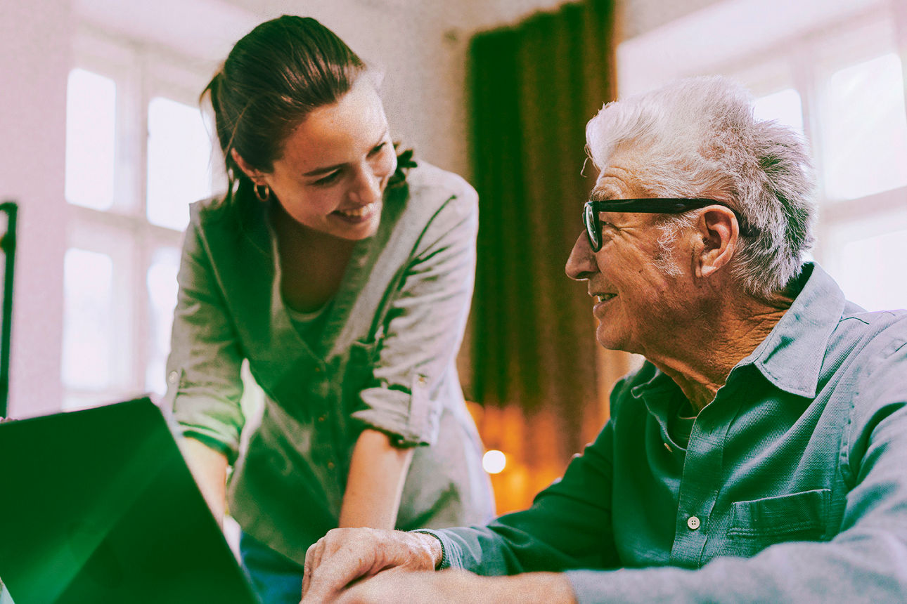 Mann sitzt vor Laptop und redet mit junger Frau