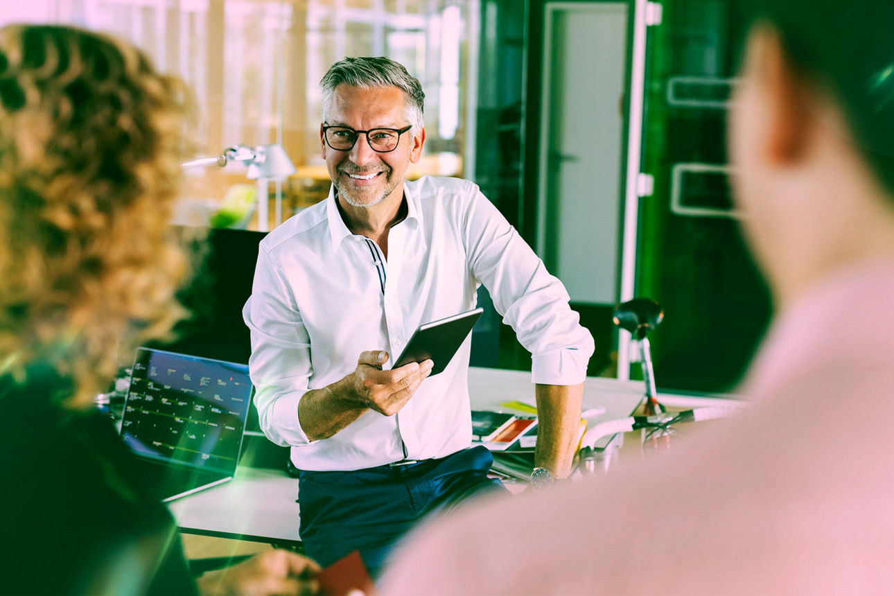 Mann mit Tablet im Austausch mit 2 Personen