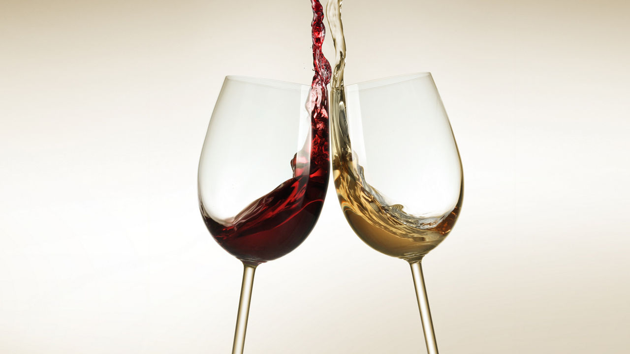 Zwei Gläser gefüllt mit Rot- und Weißwein auf einem goldfarbenen Hintergrund