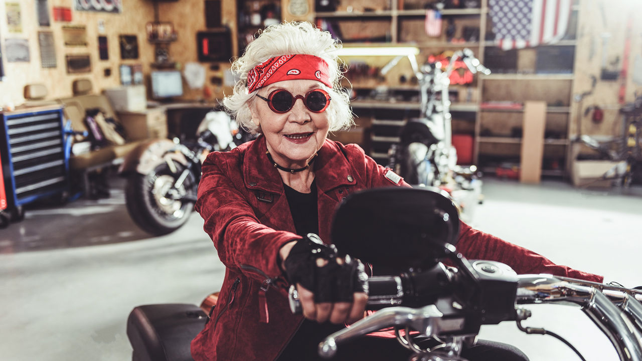 Coole ältere Frau mit Sonnenbrille auf Motorrad