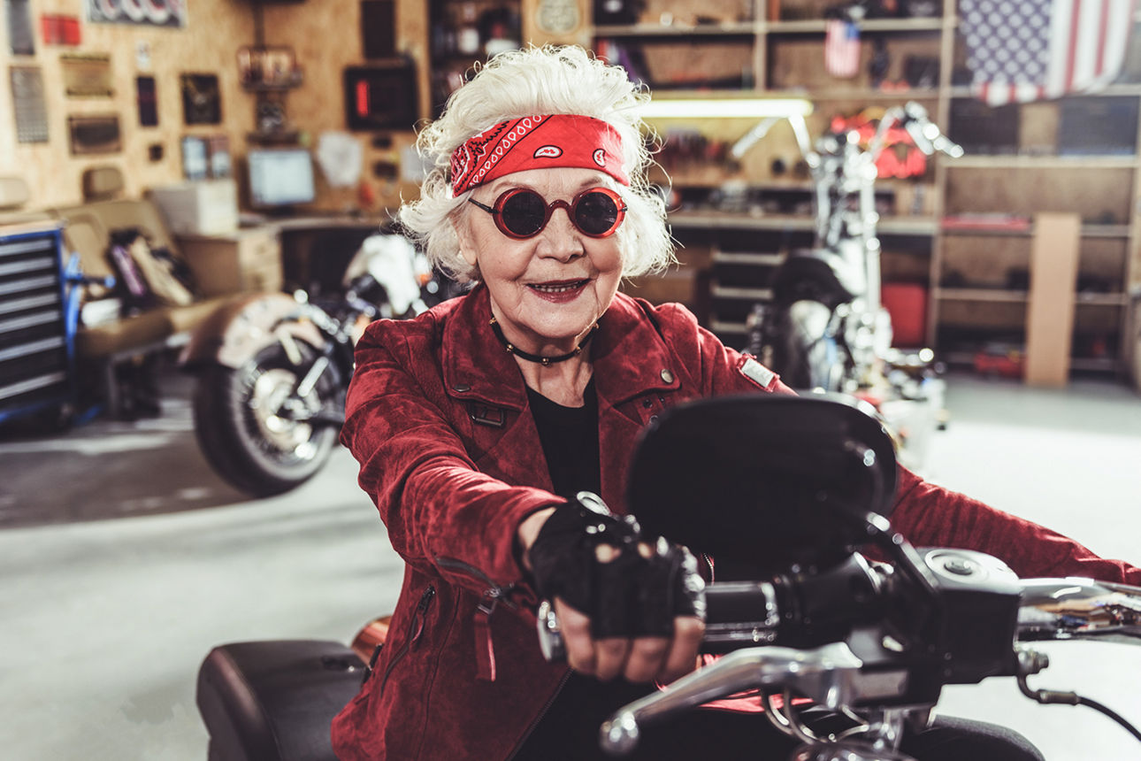 Coole ältere Frau mit Sonnenbrille auf Motorrad