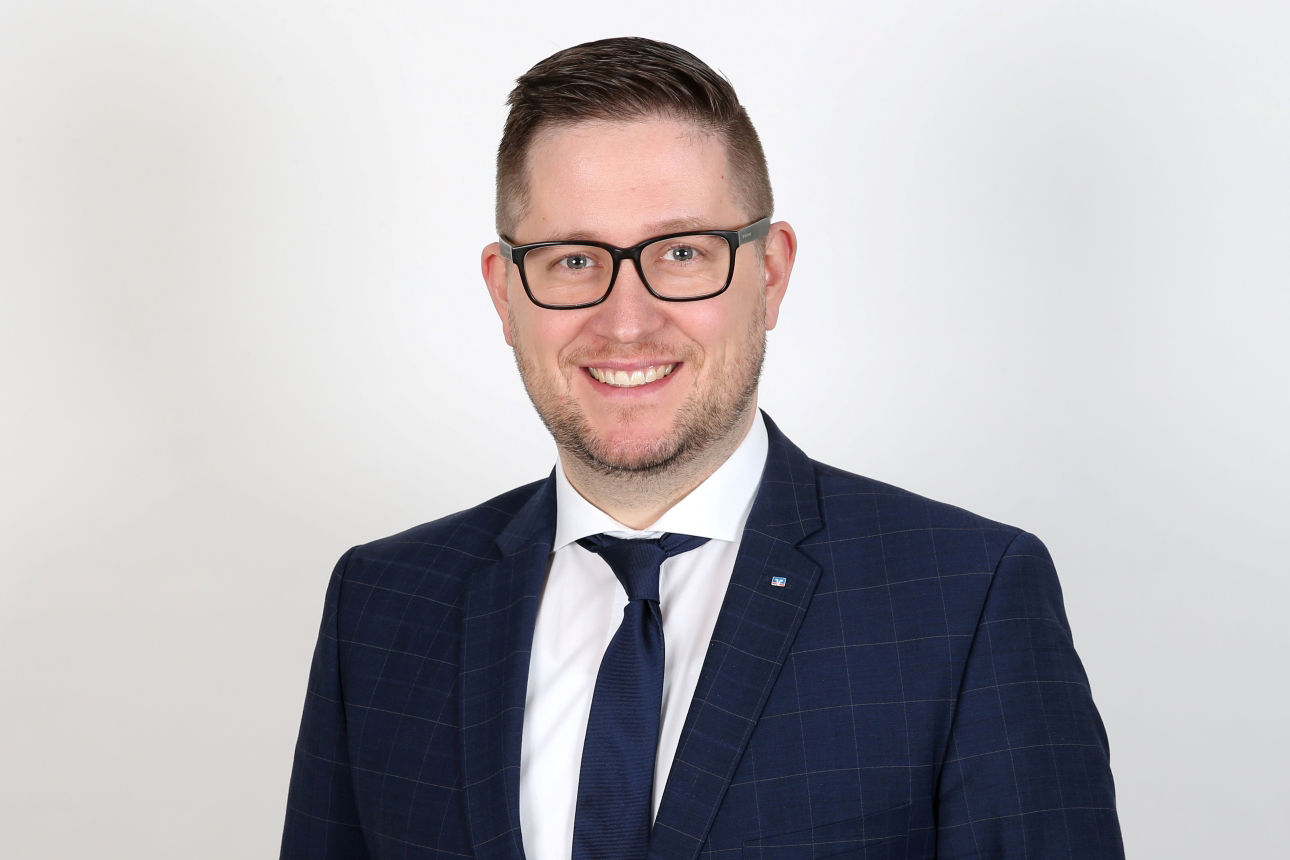 Ein lächelnder Mann schaut in die Kamera.