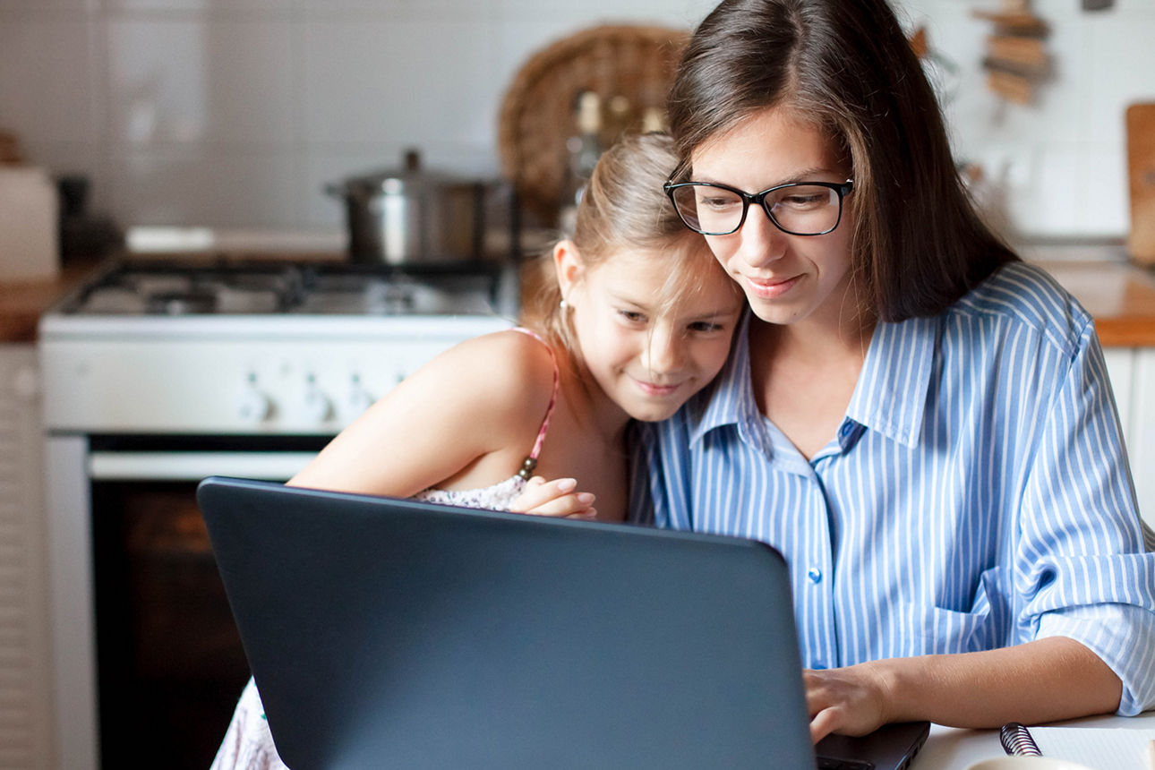 Junge Familie sitzt in Küche vor dem Laptop