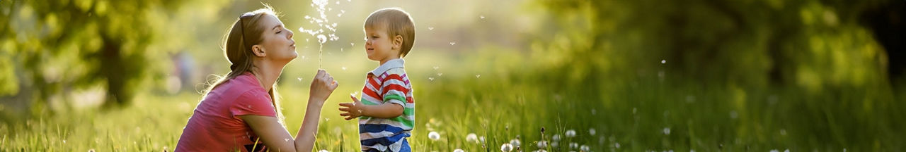 Mutter und Kind pusten Pusteblume