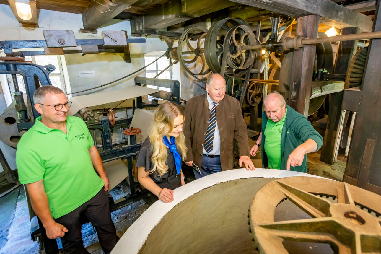 450 Jahre Neumannmühle – Als das Kirnitzschtal vom Klang der Sägen erfüllt war06.06.2026, Kirnitzschtal, Sebnitz, Neumannmühle Kirnitzschtal. Im Jahr 2026 erinnerte die traditionsreiche Anlage an ein außergewöhnliches Jubiläum: Vor 450 Jahren, am 2. September 1576, wurde die Neumannmühle erstmals urkundlich erwähnt. Was damals als einfache Brettmühle am Eingang des Großen Zschands begann, entwickelte sich zu einem bedeutenden Zeugnis der Wirtschafts- und Technikgeschichte der Sächsischen Schweiz. Dabei reichte die Geschichte vermutlich noch weiter zurück. Historiker vermuteten, dass bereits im 14. Jahrhundert an dieser Stelle eine kleine Schneidemühle gestanden hatte. Sicher belegt war jedoch erst die Erwähnung von 1576 in einem Verzeichnis des Amtes Hohnstein. Dort wurden an der Einmündung des Großen Zschands in das Kirnitzschtal zwei Brettmühlen genannt – eine davon war die heutige Neumannmühle.Mit dem Beginn der Holzflößerei auf der Kirnitzsch gegen Ende des 16. Jahrhunderts gewann die Mühle zunehmend an Bedeutung. Das Tal wurde zu einer wichtigen Verkehrsader für den Holztransport. Baumstämme aus den Wäldern der Hinteren Sächsischen Schweiz gelangten auf dem Wasserweg zu den Sägemühlen, wo sie zu Bau- und Nutzholz verarbeitet wurden. Die Neumannmühle profitierte von dieser Entwicklung und wurde über Generationen hinweg zu einem wichtigen Wirtschaftsbetrieb der Region. Besonders bemerkenswert war die Technik, die sich bis heute erhalten hat. Der älteste Teil der Mühle blieb über Jahrhunderte nahezu unverändert. Herzstück war ein Ein-Blatt-Sägegatter venezianischer Bauart – eine Konstruktion, die als technisches Meisterwerk ihrer Zeit galt. Während vielerorts historische Mühlentechnik verschwand, überdauerte sie in der Neumannmühle die Jahrhunderte nahezu im Originalzustand. Das mehr als vier Jahrhunderte alte Sägegatter gehört heute zu den bedeutendsten technischen Zeugnissen seiner Art in Sachsen.Einen weiteren Meilenstein erlebte die Mühle in den Jahren 1871 und 1872. Damals entstand ein Anbau für eine Holzschleiferei. Hier wurde Holzschliff hergestellt – jener Rohstoff, der die industrielle Papierproduktion revolutionierte. Täglich entstanden bis zu 300 Kilogramm Holzschliff, die in Papierfabriken der Umgebung weiterverarbeitet wurden. Die Neumannmühle schlug damit die Brücke zwischen traditionellem Handwerk und beginnender Industrialisierung. Angetrieben wurde die gesamte Anlage von der Kraft des Wassers. Das große Wasserrad setzte die Maschinen in Bewegung und lieferte eine Leistung von bis zu 18 Pferdestärken – lange bevor Elektrizität Einzug hielt. Für die Menschen jener Zeit war die Wasserkraft die Grundlage ihres wirtschaftlichen Erfolges.Nach dem Ende der Holzschliffproduktion im Jahr 1945 und der Einstellung des Sägebetriebes in den 1950er Jahren schien das Schicksal der Mühle zunächst besiegelt. Die Gebäude verfielen, die Technik rostete. Doch Heimatforscher, Denkmalpfleger und engagierte Bürger erkannten früh den unschätzbaren Wert der Anlage. Bereits in den 1960er Jahren begannen erste Bemühungen, die Mühle als technisches Denkmal zu sichern. Nach Jahren des Verfalls wurde sie ab den 1990er Jahren aufwendig restauriert. Seit der Gründung des Vereins „Schauanlage Neumannmühle e. V.“ im Jahr 1998 sorgten zahlreiche Ehrenamtliche dafür, dass die Geschichte der Mühle nicht in Vergessenheit geriet.So stand die Neumannmühle auch 450 Jahre nach ihrer ersten urkundlichen Erwähnung noch immer dort, wo Generationen von Müllern, Sägern und Handwerkern gearbeitet hatten. Als einzige Mühle im Kirnitzschtal hatte sie ihre ursprüngliche Gestalt weitgehend bewahrt. Sie war längst mehr als ein Museum. Sie war ein lebendiges Geschichtsbuch aus Holz, Stein und Eisen – ein Ort, an dem die Vergangenheit nicht nur erzählt, sondern erlebt werden konnte.Als sich am 6. Juni 2026 Förderer, Vereinsmitglieder, Freunde und Gäste im Technischen Denkmal versammelten, feierten sie deshalb nicht allein ein Jubiläum. Sie würdigten 450 Jahre Arbeit, Erfindergeist und Heimatgeschichte – und jene Menschen, die dafür gesorgt hatten, dass das alte Wasserrad im Kirnitzschtal auch für kommende Generationen nicht stillstehen würde.Foto: Marko Förster06.06.2026 © Marko FörsterWICHTIGE HINWEISE: Jeder Abdruck ist honorar- und umsatzsteuerpflichtig (7 % Ust.)! Die Weitergabe des Bildmaterials an Dritte ist verboten!