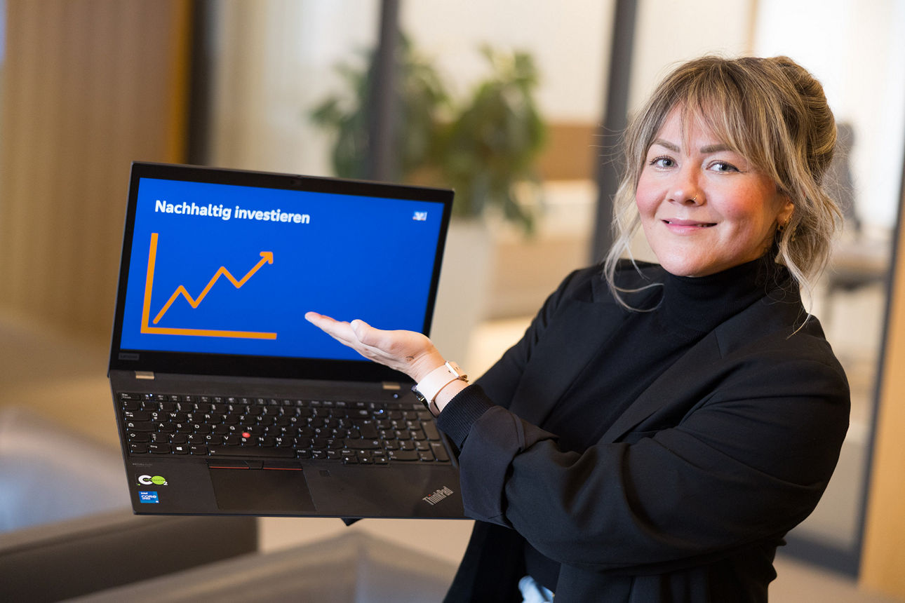 Mitarbeiterin zeigt auf ihrem Laptop eine Grafik zum Thema „Nachhaltig investieren“.
