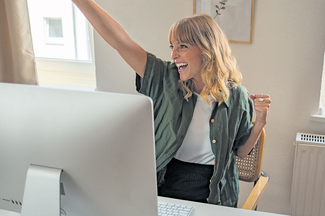 Frau freut sich vor Computer