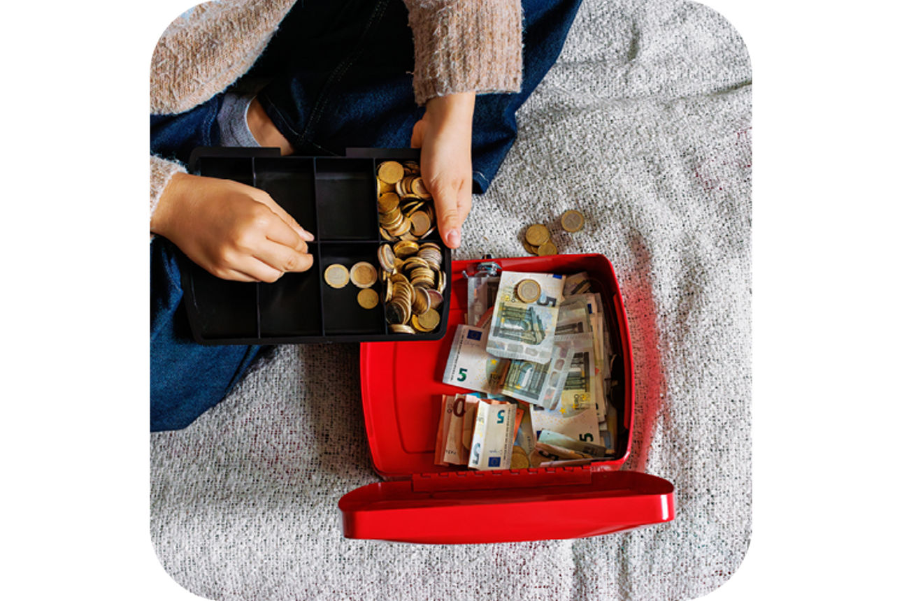 Frau die Geld in eine kleine Kasse umfüllt