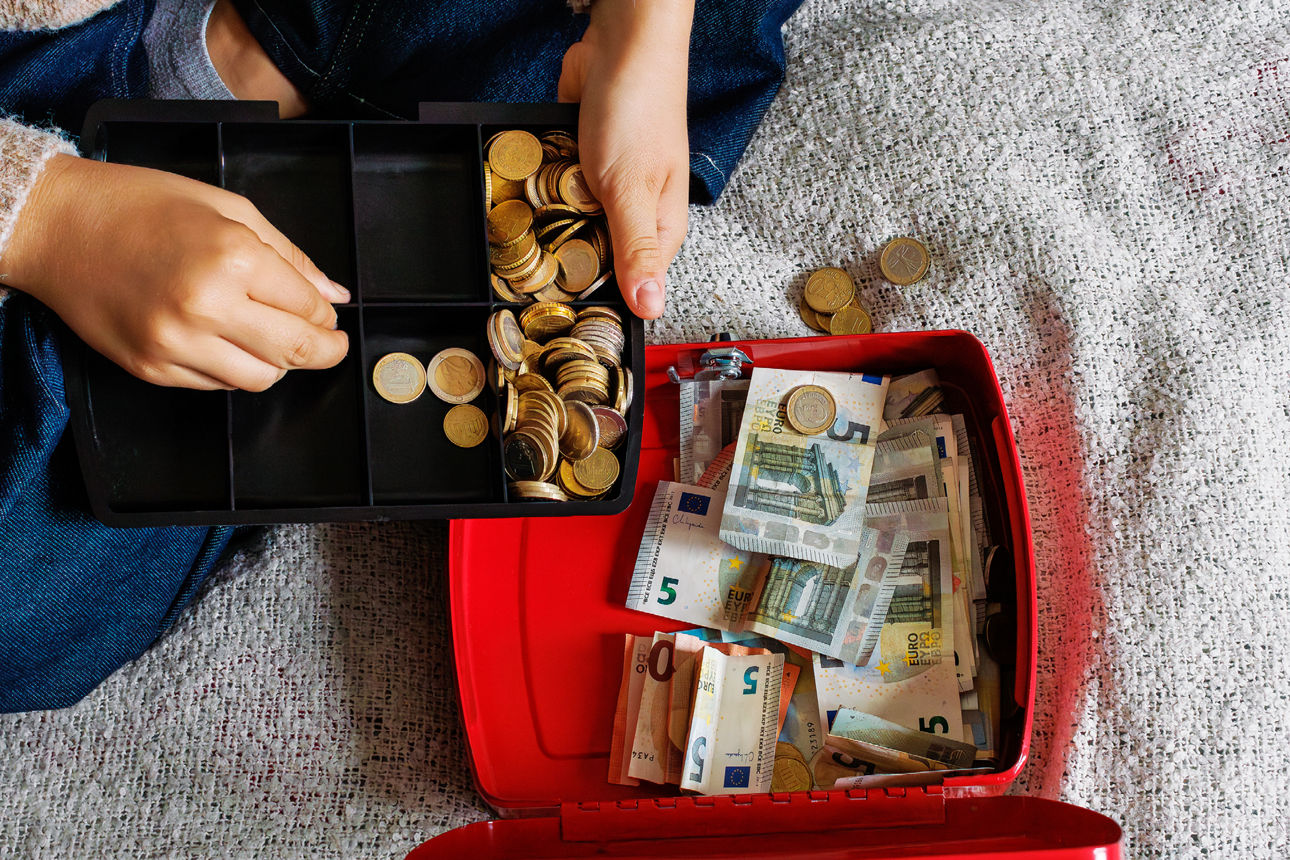 Frau die Geld in eine kleine Kasse umfüllt
