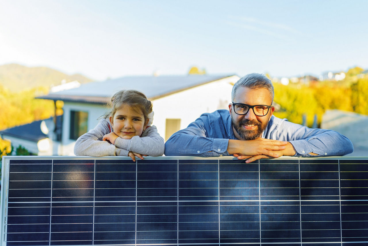 Junge Tochter und Vater lehnen auf einem Photovoltaikpanel