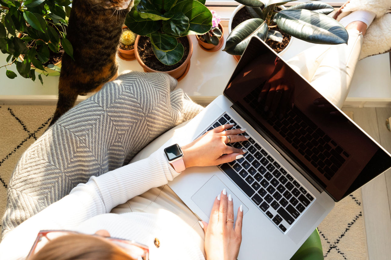 Eine Frau hat einen Laptop auf dem Schoß und legt die Beine überkreuzt auf einem Tisch ab
