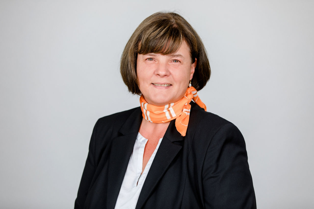 Eine lächelnder Frau schaut in die Kamera.