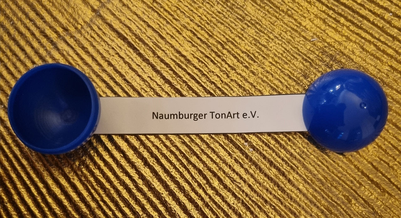 Der Name Naumburger TonArt e. V. steht auf einem Papierschnipsel, der aus einer Loskugel guckt