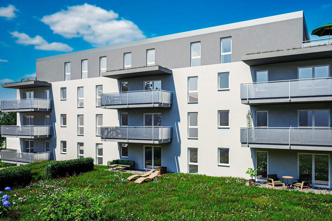Mehrstöckiges Wohngebäude mit Balkonen und begrüntem Dach, umgeben von einer großen Rasenfläche mit Sträuchern.