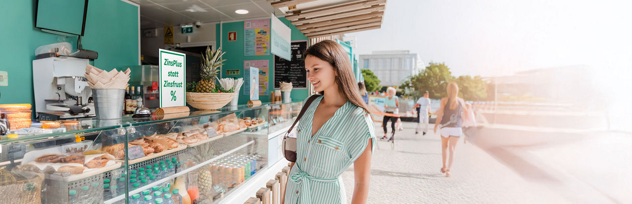 Junge Frau steht vor einer Essensvitrine eines Foodtrucks