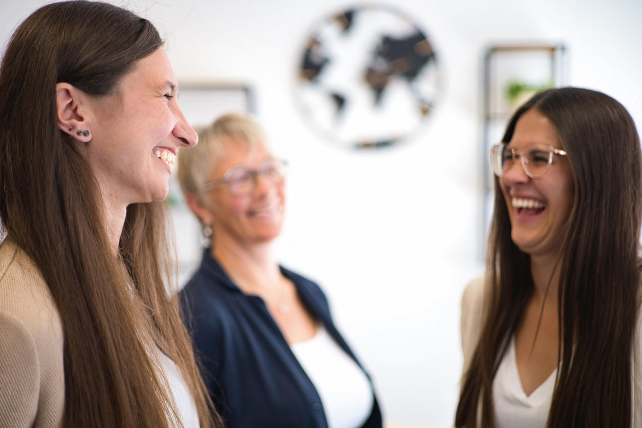 Drei lächelnde Frauen unterhalten sich
