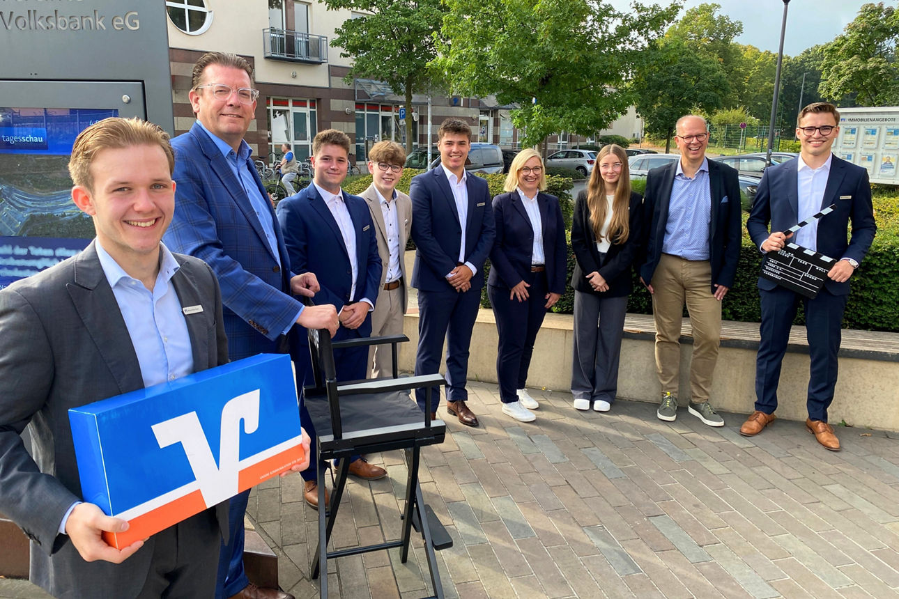 Sechs neue Azubis mit Mitarbeiter stehen vor der Volksbank