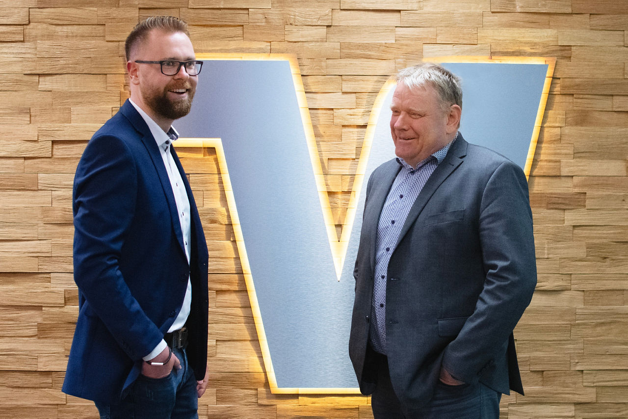 Unsere Mitarbeiter Andrè Butzmühlen und Rolf Jansen vor einem leuchtenden Volksbank "V"