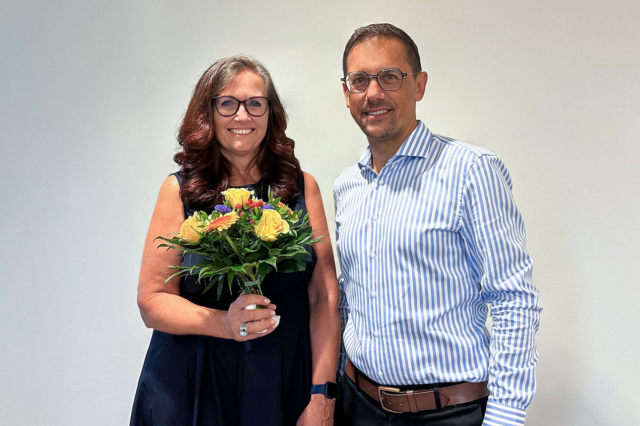 Die neue Mitarbeiterin der Volksbank mit einem Blumenstrauß und einem Herren neben ihr. 
