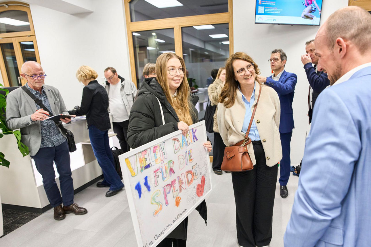 Das Bild zeigt die Übergabe eines Kindergartenbildes an Filialleiter Simon Schell