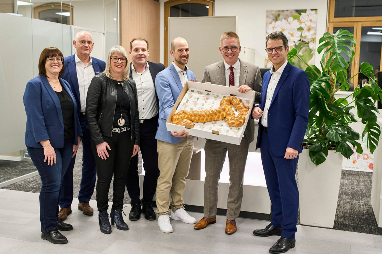 Das Bild zeigt das Team der Filiale Rust mit Dr. Kai-Achim Klare und Vorstand Peter Rottenecker bei der "Schlüsselübergabge" in Form einer Backbrezel