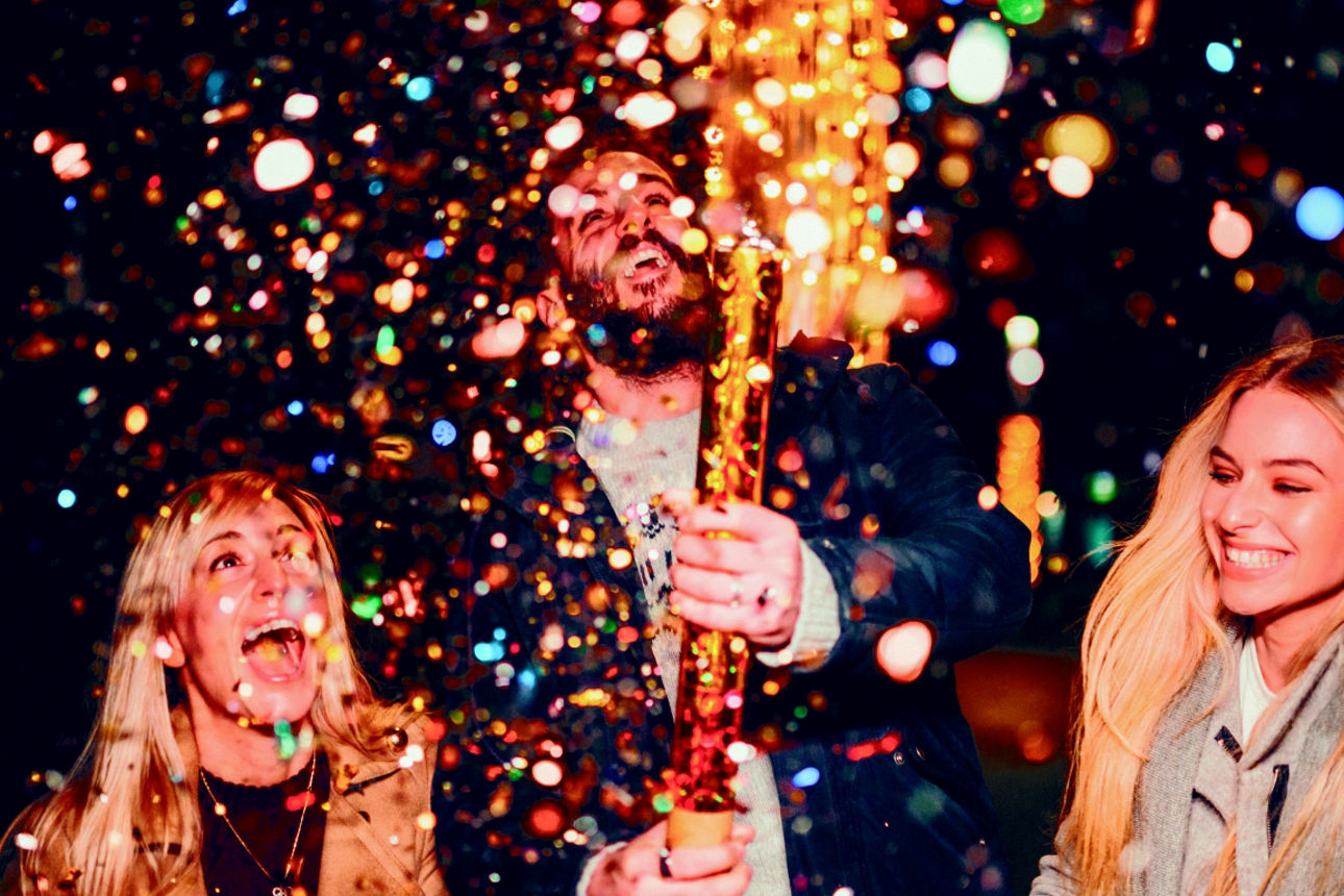 Ein Mann feuert lachend eine Konfettikanone ab