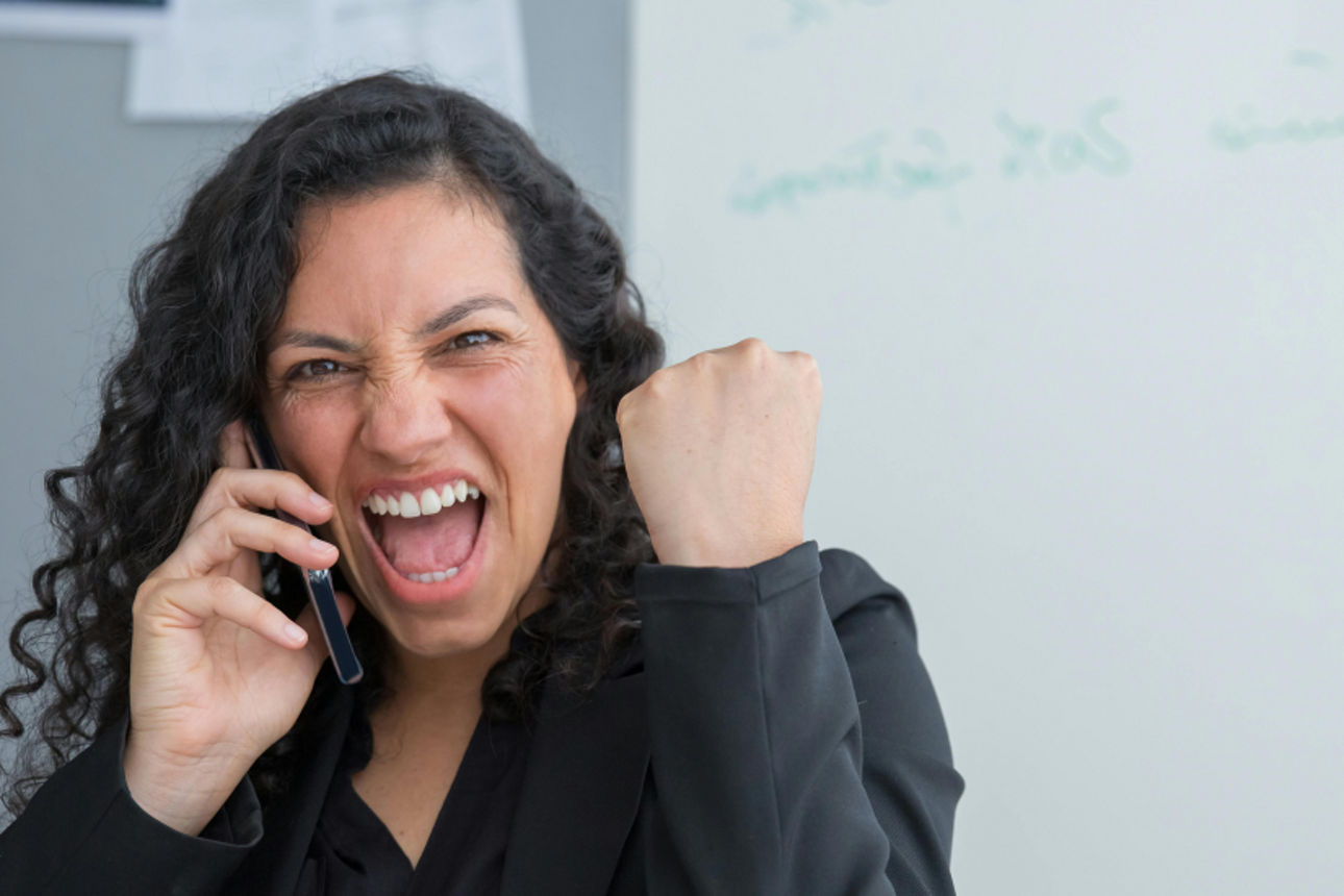 Frau telefoniert, hebt die Faust und freut sich