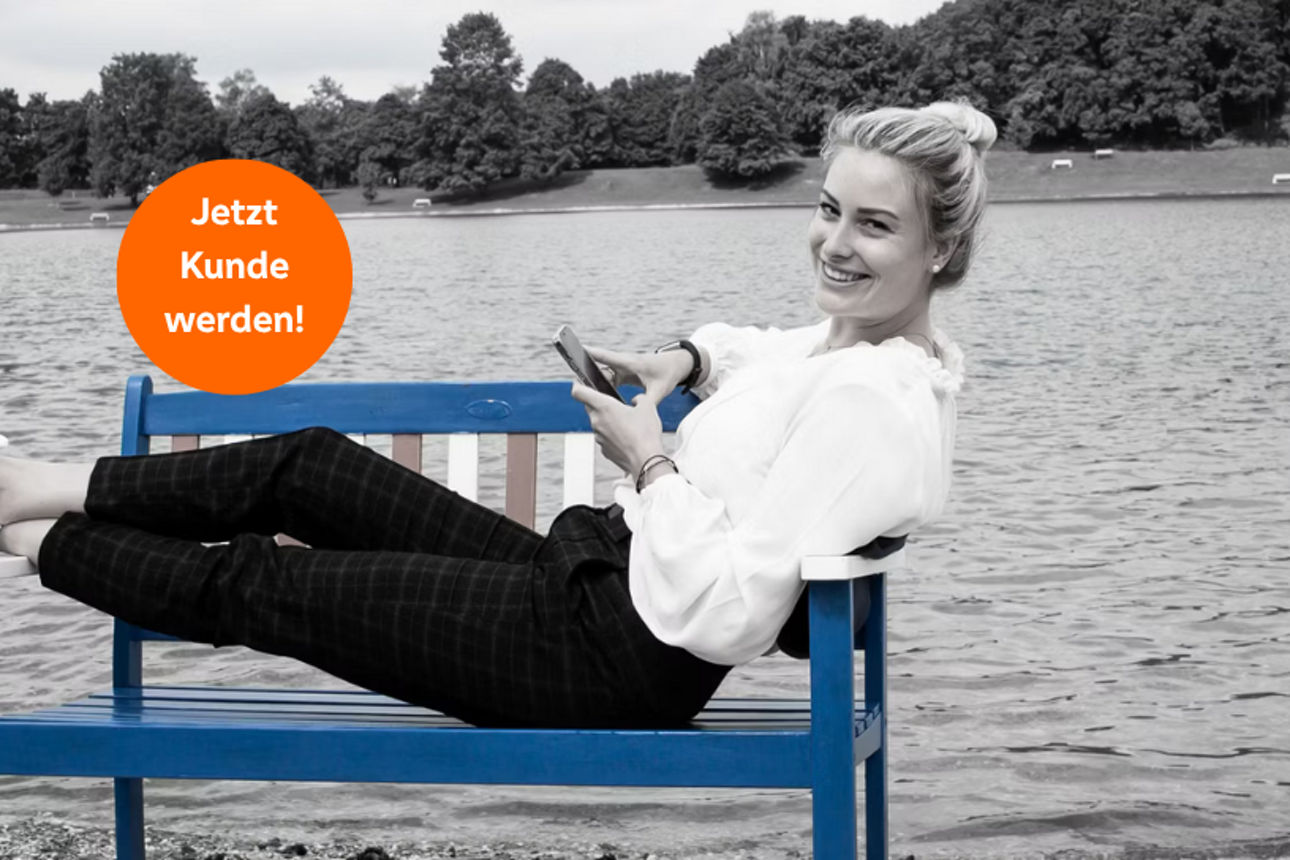Frau liegt auf einer Holzbank am Ufer eines Sees
