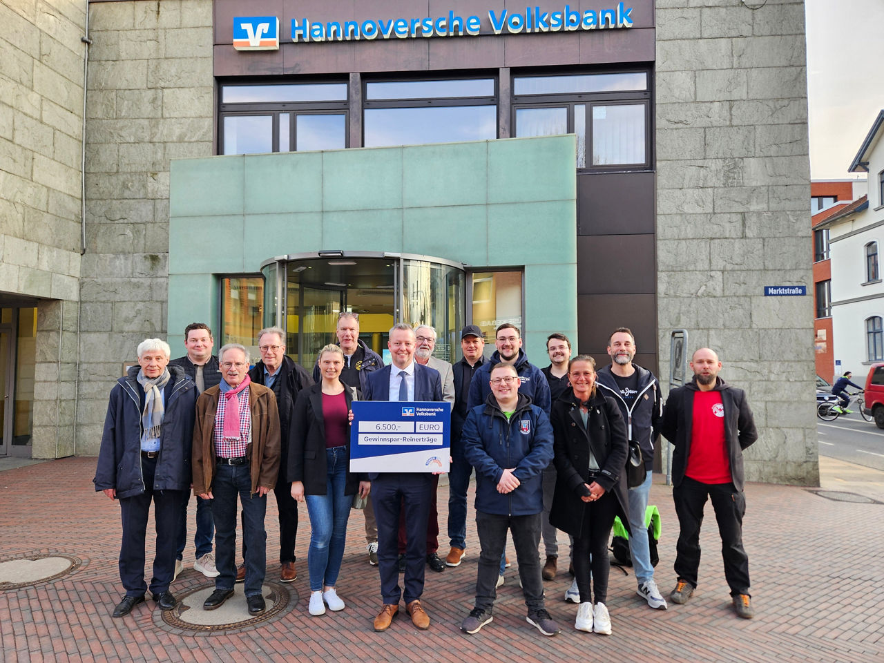 Viele Mitarbeiter stehen in einer Reihe mit einem Schild mit der Aufschrift "6500 EURO Gewinnspar-Reinerträge