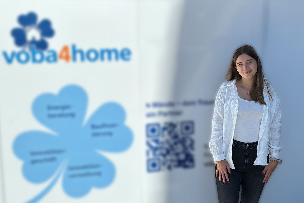 Eine Frau steht vor dem voba4home Banner und lächelt in die Kamera