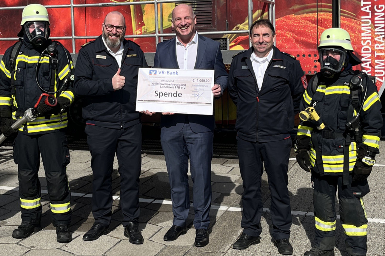 Drei Herren und drei Feuerwehrmänner mit einem Scheck. 