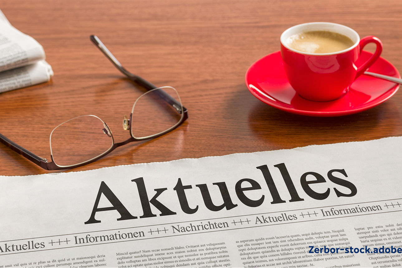 Zeitung liegt auf einem Tisch, daneben eine Tasse und eine Brille 