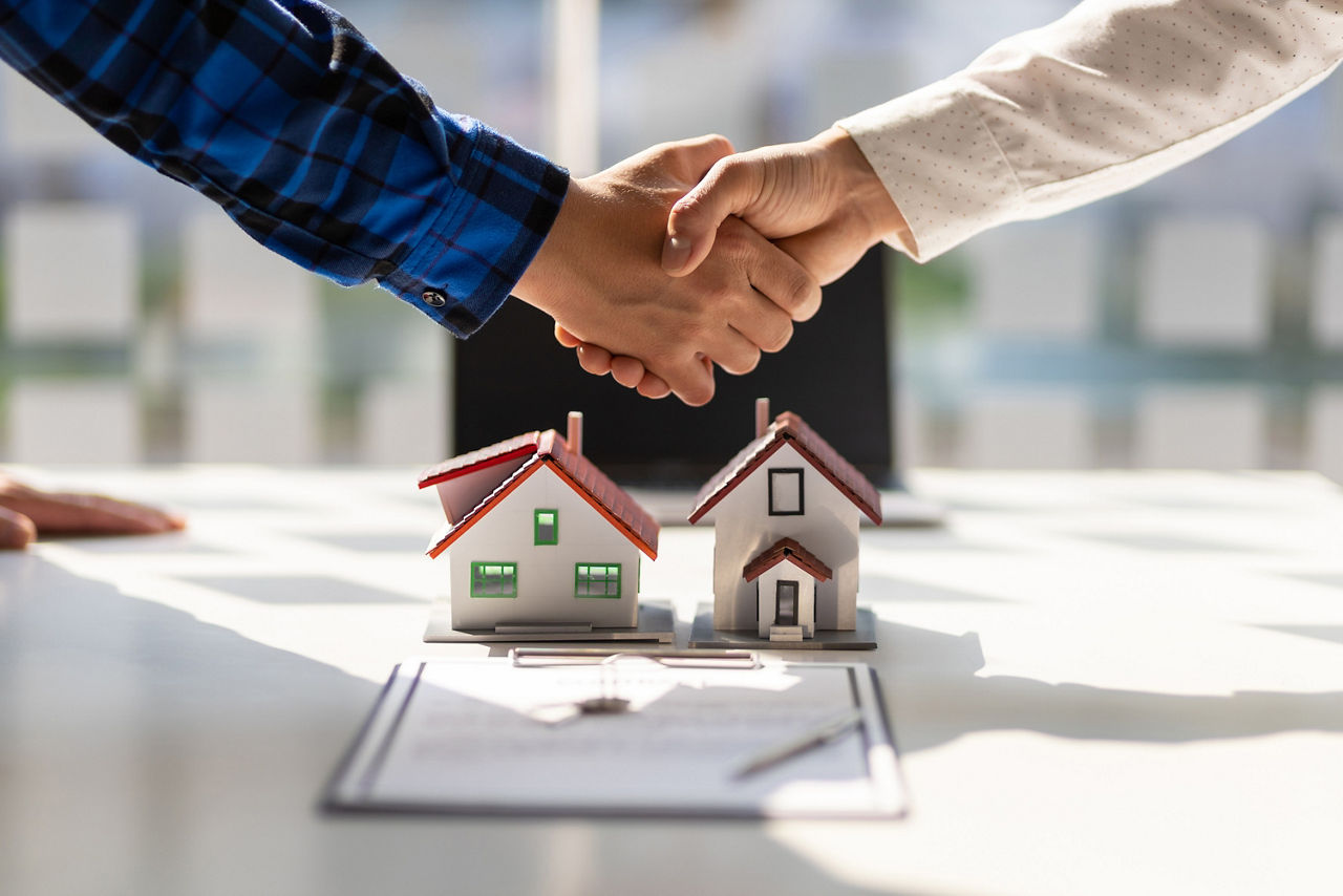 Immobilienmakler schütteln sich nach Abschluss der Vertragsunterzeichnung die Hand.