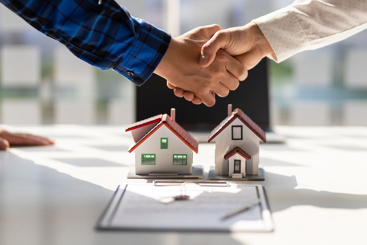 Immobilienmakler schütteln sich nach Abschluss der Vertragsunterzeichnung die Hand.