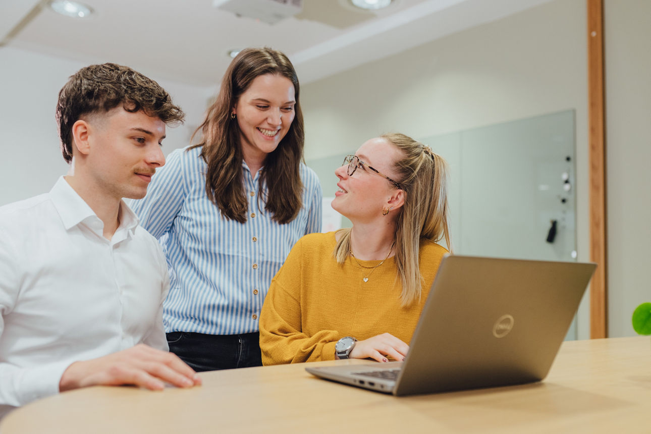 Drei Mitarbeitende sitzen am Tisch und unterhalten sich