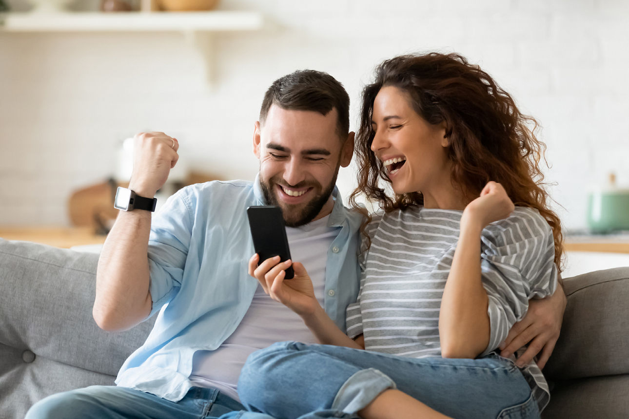 Mann und Frau freuen sich und schauen auf Ihr Handy