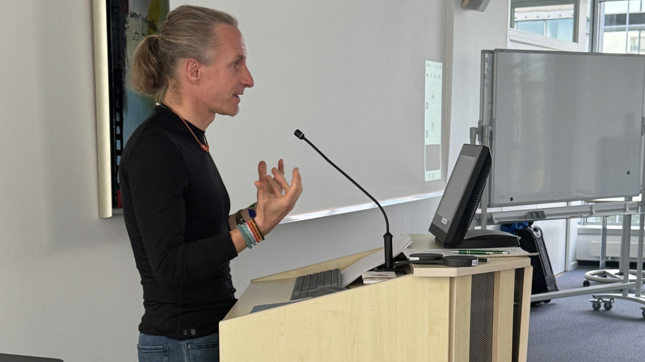 Norman Bücher steht hinter einem Pult und trägt vor.