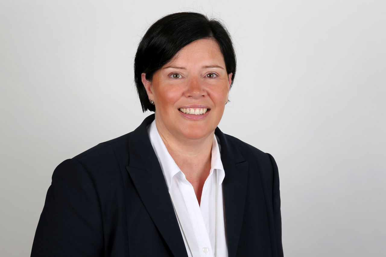 Eine lächelnder Frau schaut in die Kamera.