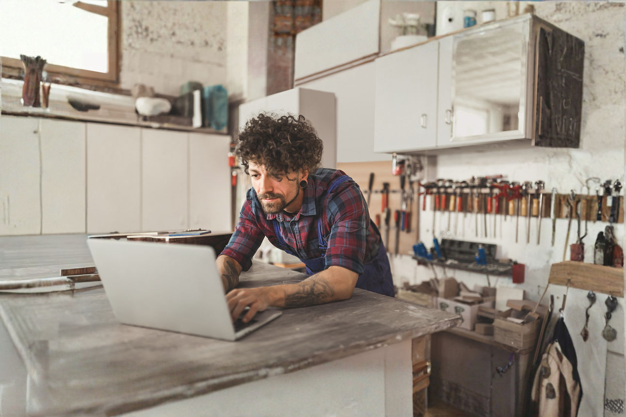 Ein junger Mann arbeitet auf seiner Werkbank an seinem Notebook
