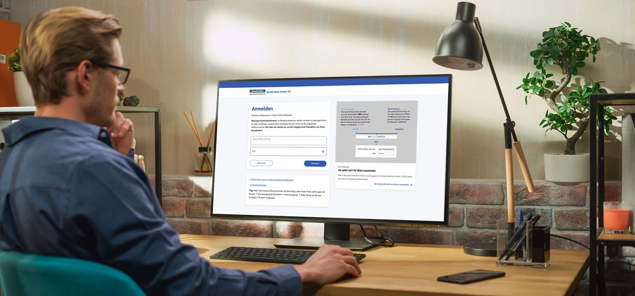 Mann sitzt am Schreibtisch und loggt sich ins Online-Banking ein