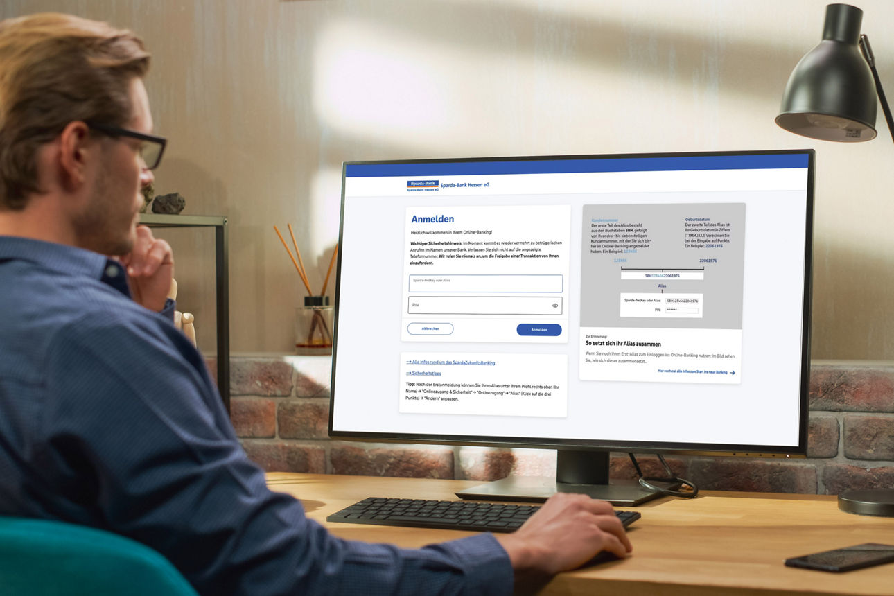 Mann sitzt am Schreibtisch und loggt sich ins Online-Banking ein