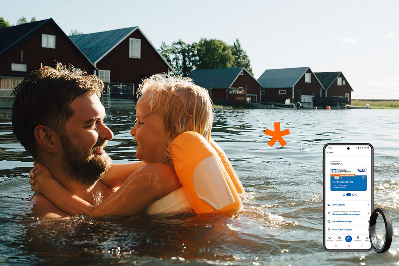 Mann und Kind mit Schwimmflügeln im See vor roten Häusern