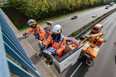 Arbeiter stehen auf Hebebühne an Autobahnbrücke