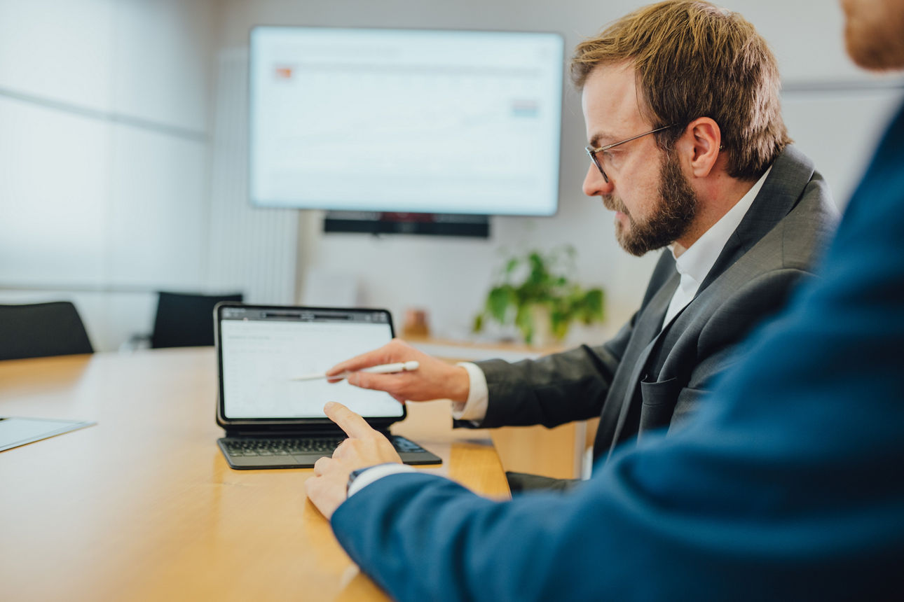 Ein Mitarbeitender zeigt einem anderen Mitarbeitenden etwas auf dem Tablet