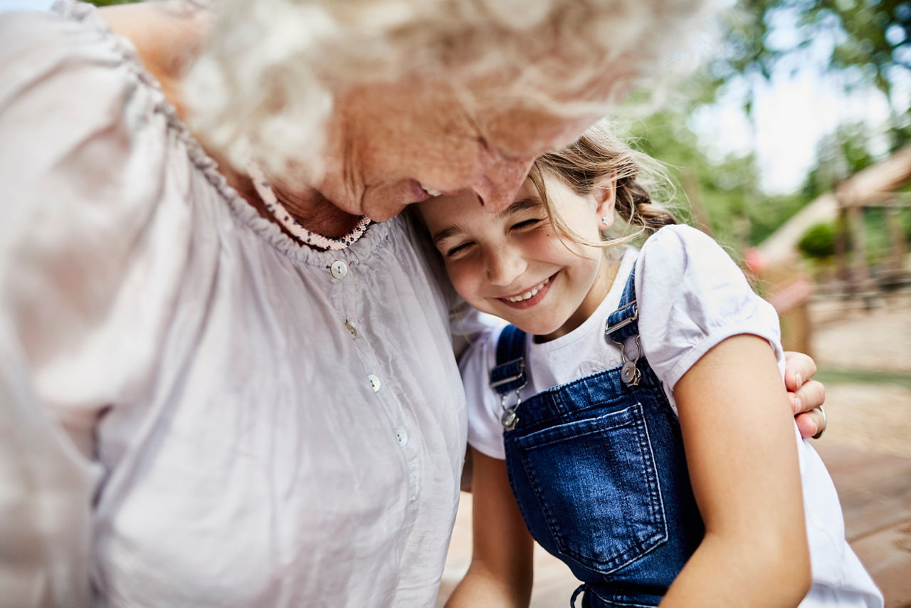 Oma hält ihre Enkelin im Arm, beide lachen
